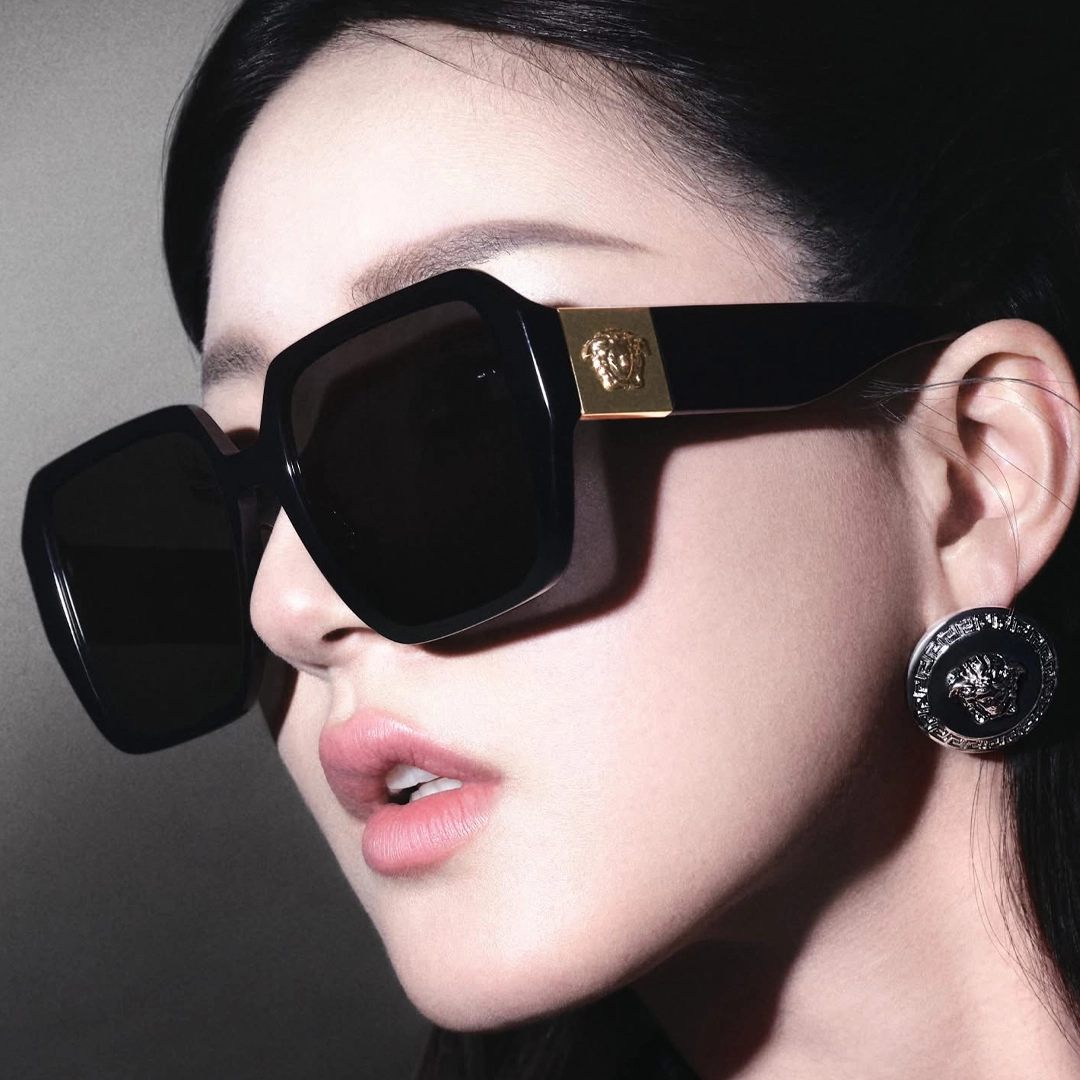 Un mannequin avec des lunettes de soleil Versace glamour et opulentes arborant l'emblème de la Méduse.